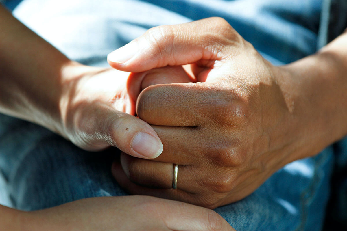 Carer holding hand of patient wearing gold wedding band