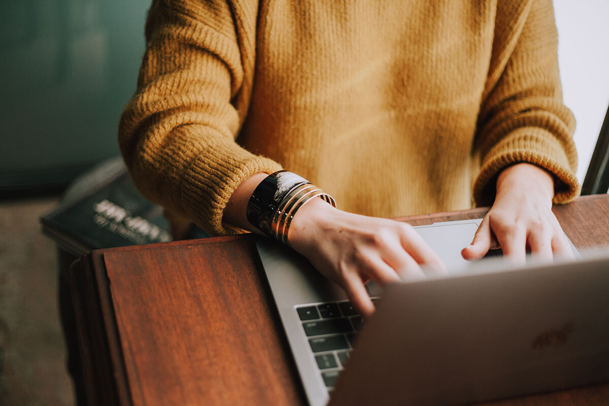person in mustard jumper with gold bangles on laptop photo