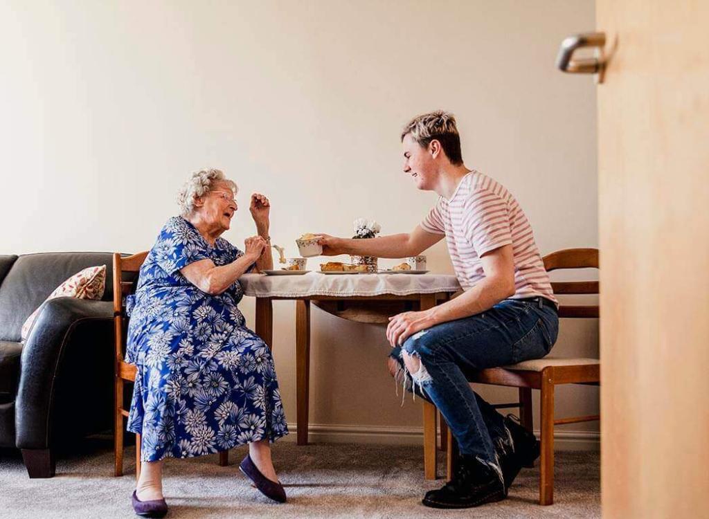 Elderly woman and young man enjoying morning tea together