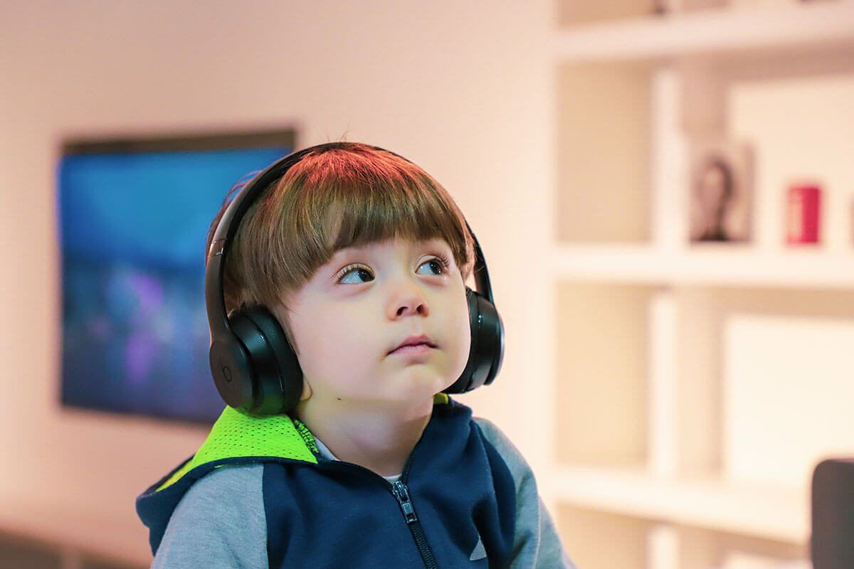 Young boy with headphones looking up at a screen