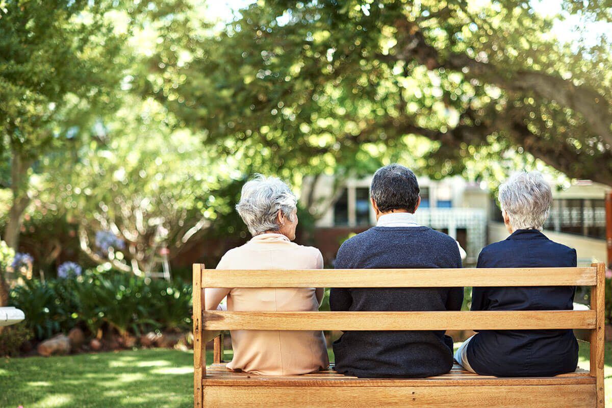 Rearview shot of a group of seniors sitting together on a bench out in the garden