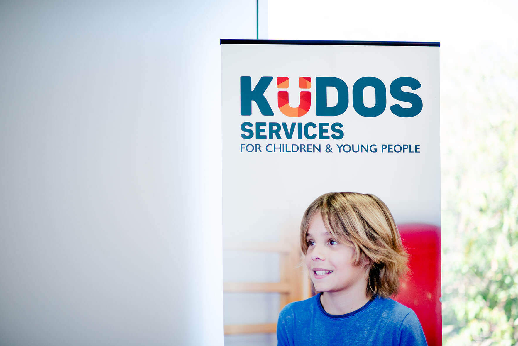 Kudos Services pull up banner with young boy, Photo by Nat Rogers