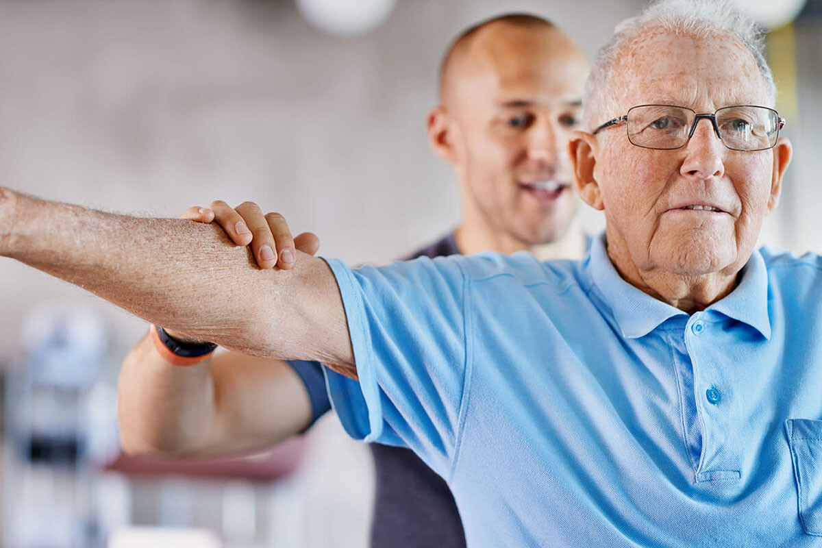 Senior man with allied health professional, doing excercise therapy