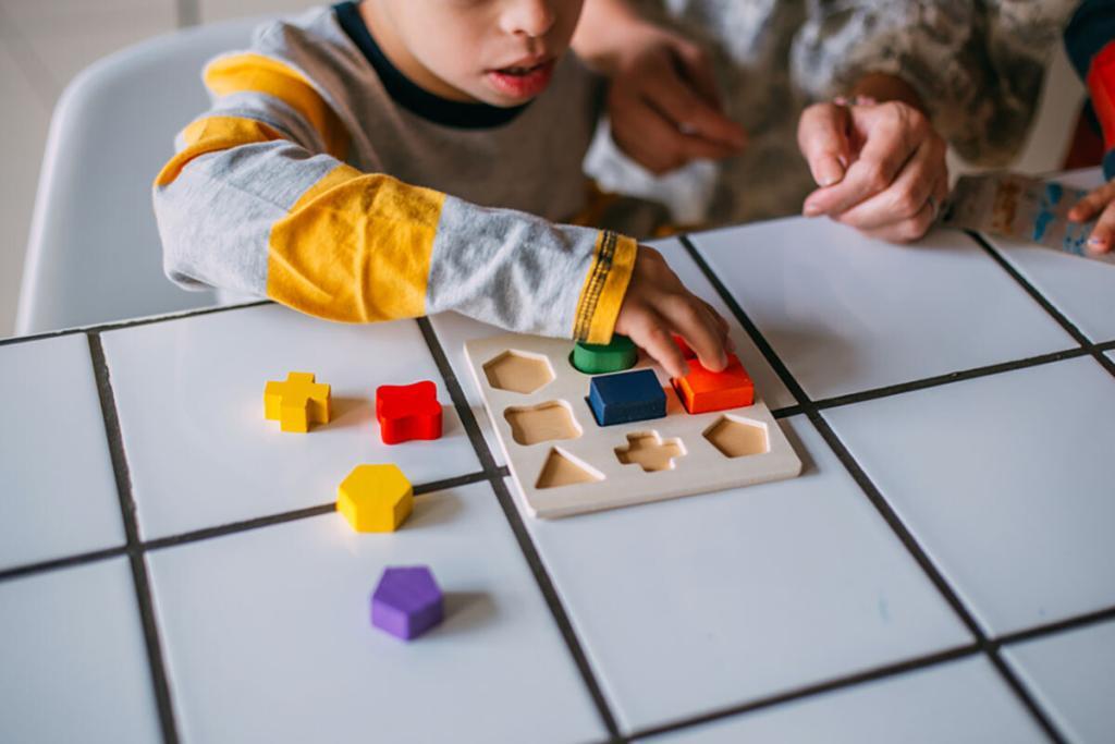 Young boy playing with building blocks with carer